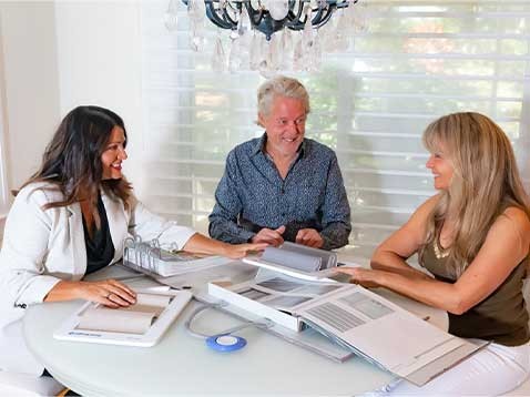 A man and two women sitting at a table looking through fabric samples