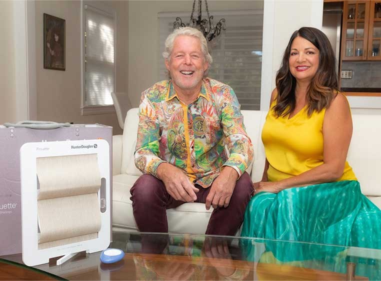 A smiling man and woman sitting on a white couch 